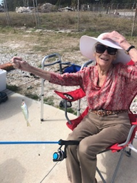 Lois assisted living resident Lois with sun hat and glasses fishing