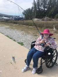 assisted living resident fishing assisted living resident wearing red sun hat fishing